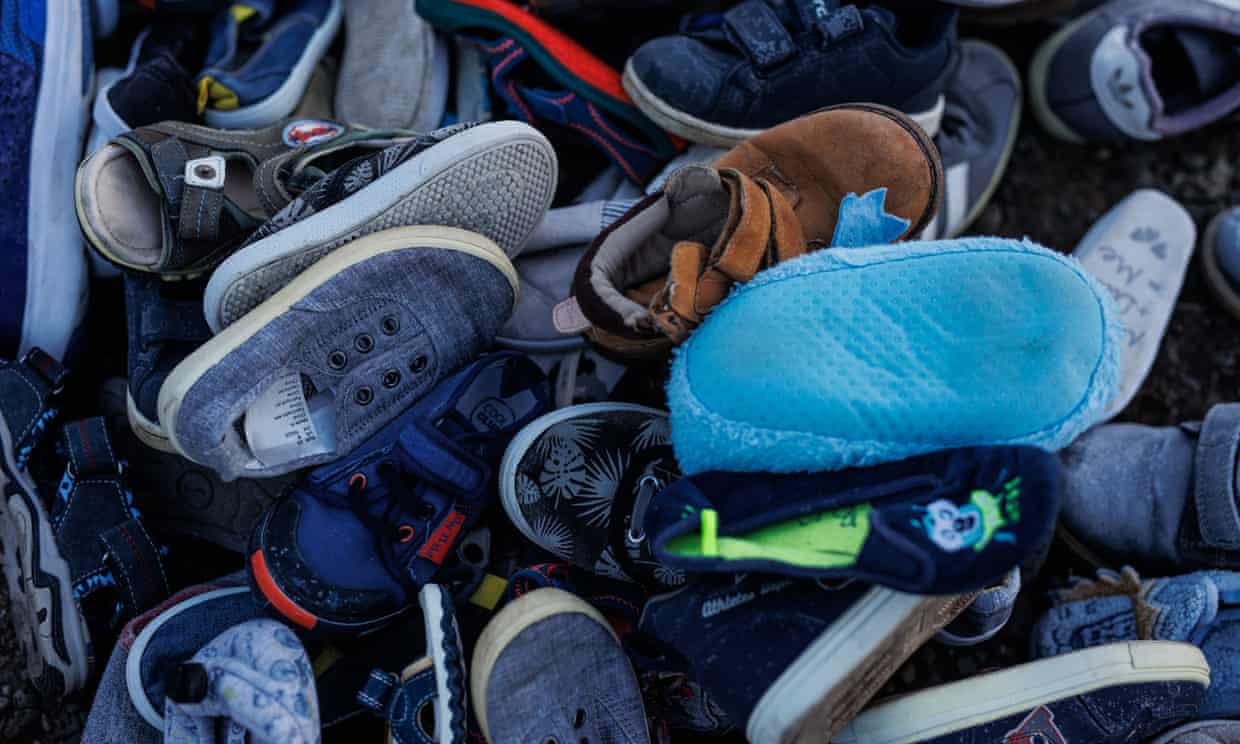 A pile of miscellaneous children's shoes and slippers, many grubby, worn, or torn, in a big, jumbled pile.