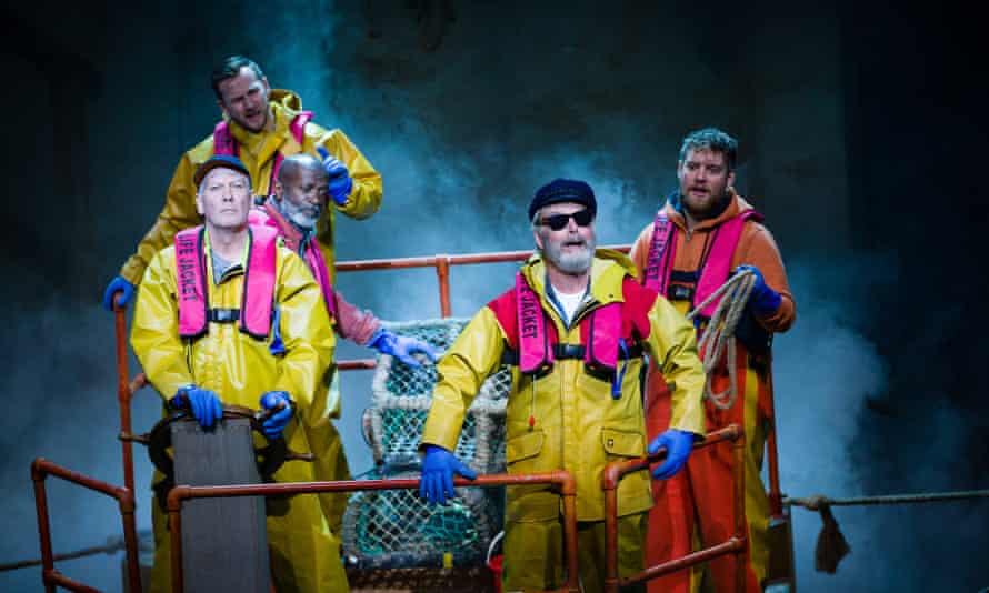 Cast dressed in fishers' yellow waterproofs on deck of ship (stage set)