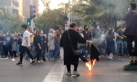 A protester in Tehran sets her veil on fire in clashes with police.