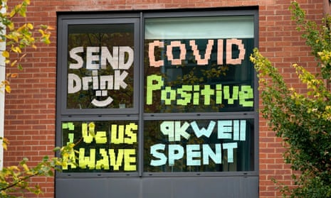 Signs made by students in a locked-down accommodation building in Manchester, reading 'Send drink', 'Covid positive', 'give us a wave' and '9k well spent'