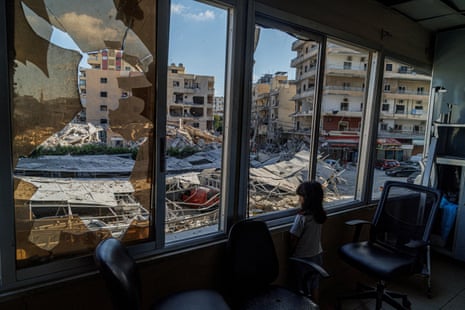A girl looks out of a broken window of a hospital.