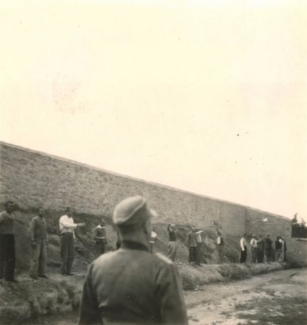 Black and white photo of men lined up along a wall