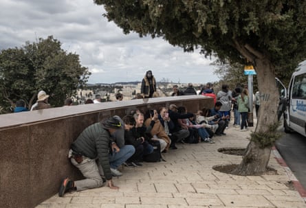 People crouched sheltering by low wall