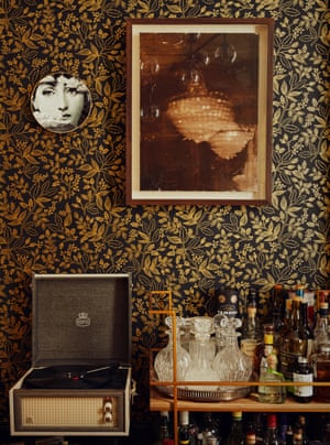 A Fornasetti plate and a painting by Julia Hamilton above a turntable and drinks trolley.