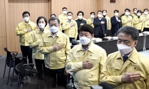 In this handout image provided by South Korean Presidential Blue House, South Korean President Moon Jae-in (3rd R) salutes during a special government meeting to discuss measures to prevent the further spread of COVID-19