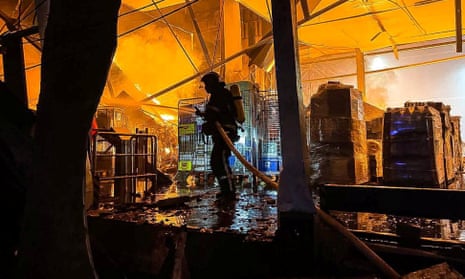 An emergency services personnel works to control a fire at a warehouse in Odesa following a Russian missile strike.