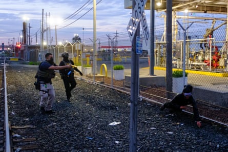 a man in tactical gear fires a taser at another man