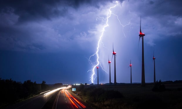 Lightning strikes behind wind turbines during a thunderstorm near the border between Germany and Poland.