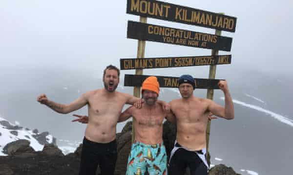 Carney mit Wim Hof und einem Mitschüler, alle mit nacktem Oberkörper, Arm in Arm und mit trotzigen Fäusten, in der Nähe des Gipfels des Kilimandscharo.