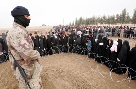 A member of the Iraqi National Guard stands near villagers queueing to vote for the national polls in a polling precinct in Al Anbar province, 243 kilometres west of Baghdad, Iraq, on 30 January 2005.