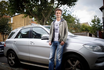 Man leans against silver car.