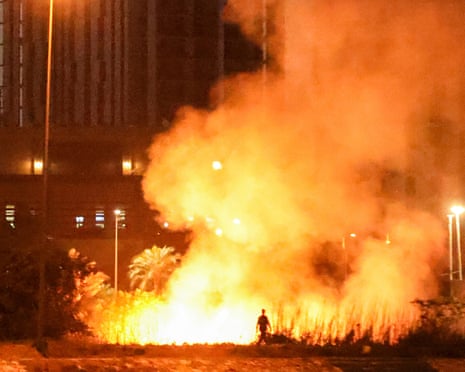 A person walks near a fire burning outside the grounds of the US embassy in Baghdad's fortified green zone on 17 March