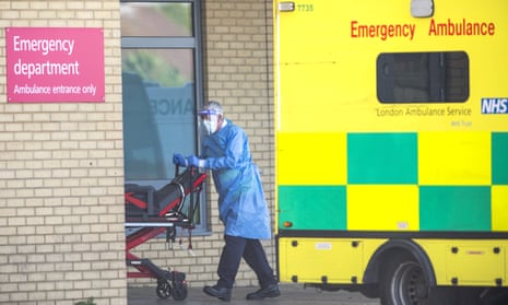 An NHS worker wheels a trolley from an ambulance