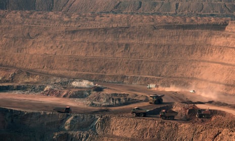 Wide shot of the mine seen from a distance. Trucks are driving around it.