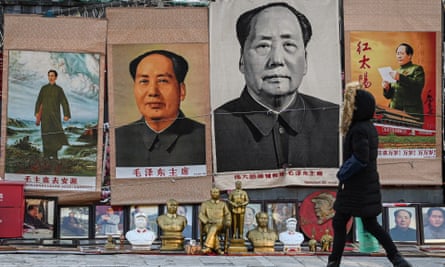 A woman walks past posters depicting the late Chinese leader Mao Zedong in Beijing
