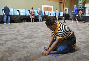 Kasharri Blacknell, a poll worker, places tape indicators for maintaining social distancing as Gwinnett County residents cast their votes during the Georgia primary election yesterday