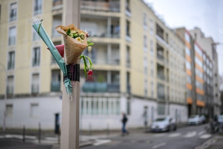 A bouquet of flowers is attached to a lamp-post, along with a set of rosary beads and a cross, at the site of the attack on Deranque.