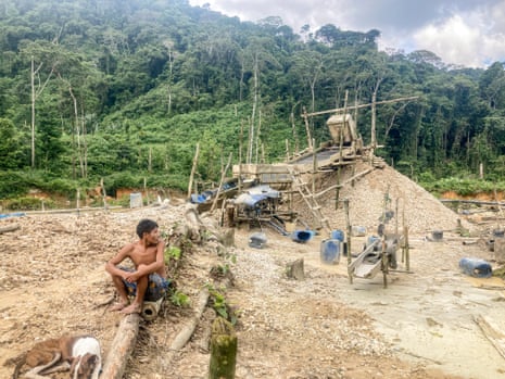 Um homem Yanomami senta-se ao lado de uma operação ilegal de mineração de cassiterita no interior do território indígena