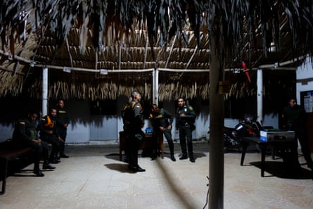 Police gather in a large thatched hut