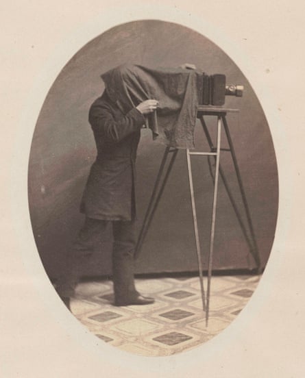 black and white photo of a person with camera, cloth over their head
