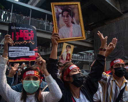 Protesters hold portraits of Aung San Suu Kyi and make three finger salutes