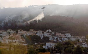 A helicopter drops fire retardant over Villes del Vent in Benitachell, near Valencia, Spain, where a wildfire has forced the evacuation of hundreds of residents and holidaymakers.