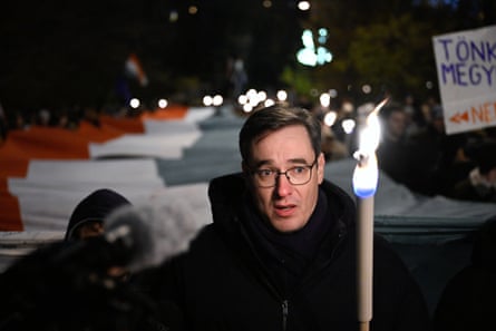 A man holds a stick with a fame outside at night
