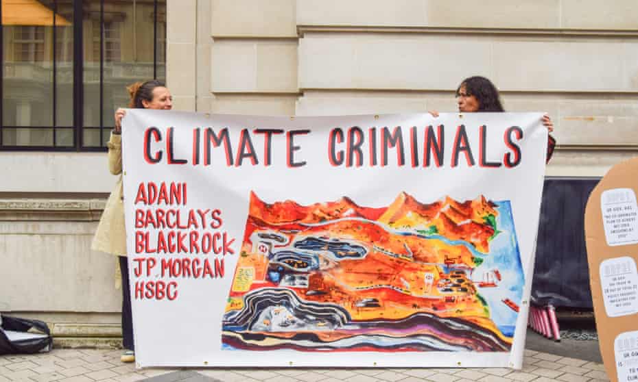Activists hold a banner calling the companies Adani, Barclays, BlackRock, JP Morgan and HSBC 'climate criminals' during the protest outside the Science Museum.