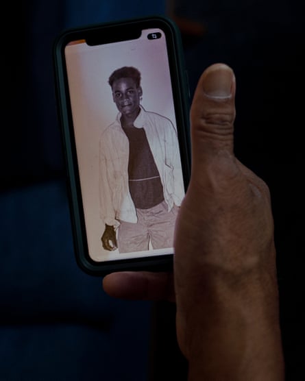 Michael Thomas’s hand holding up a phone with a photo of him when he was a teenager
