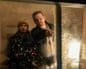 Director Zach Cregger points through a window beside Austin Abrams holding camera equipment on set