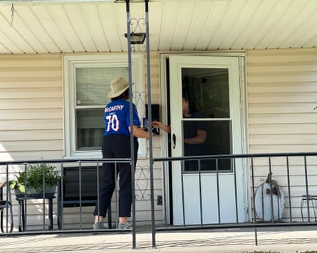 a woman speaks to a person standing inside the door of a house