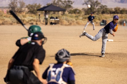 A pitcher who has just released the ball faces a batter, bat raised and blurry in the foreground.