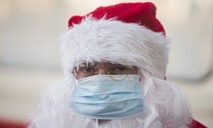 A person wearing a Santa Claus outfit and a mask for protection against Covid-19