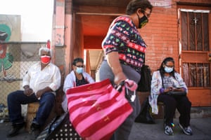 Residents wear face masks as they sit on a sidewalk in El Paso as a woman walks past on November 18.