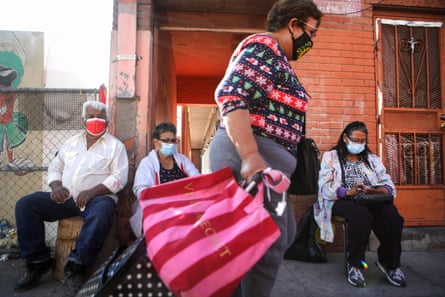 Residents wear face masks as they sit on a sidewalk in El Paso as a woman walks past on 18 November.