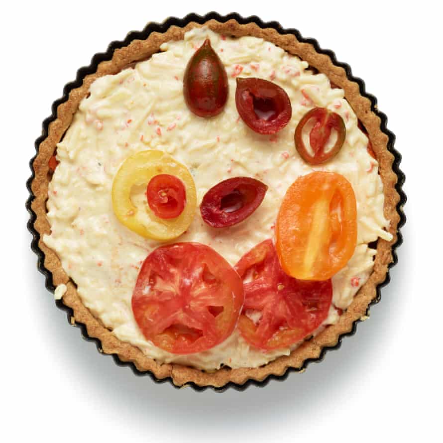 Para armar el pastel, esparza el queso restante sobre la base, luego mezcla los tomates pera horneados con la mezcla de cebolla y colócalos encima. Unte encima la mezcla de mayonesa y luego termine con los tomates escurridos.