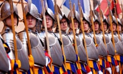 a line of Swiss Guards in blue, red and yellow uniforms with metal breastplates and helmets holding halberds