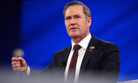 a man in a suit speaking with a hand gestured