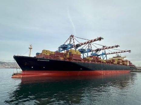 एक बंदरगाह के पास समुद्र में मालवाहक जहाज का चित्र।