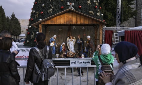 People take pictures of the Christmas tree and nativity scene in Manger Square, outside the Church of the Nativity in Bethlehem, West Bank.
