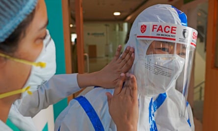 A colleague helps a nurse put on PPE in Max hospital, New Delhi.