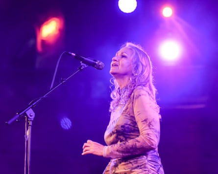 She sings into a microphone on stage