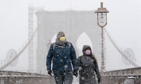 A couple wearing masks walk on the Brooklyn Bridge in New York City, as a winter snowstorm walloped the eastern US on Monday.
