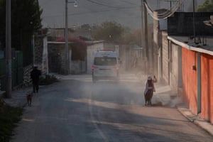 A resident sweeps away ash in a street in San Nicolás de Los Ranchos in Puebla state