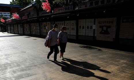 Women wearing protective masks walk past closed shops near the Sensoji temple in Tokyo