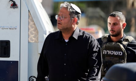 Itamar Ben-Gvir looking to the left with a soldier behind him