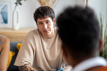 Young man listening to a friend. Young man listening attentively to a friend while meeting in a house. Friendship and support concept.