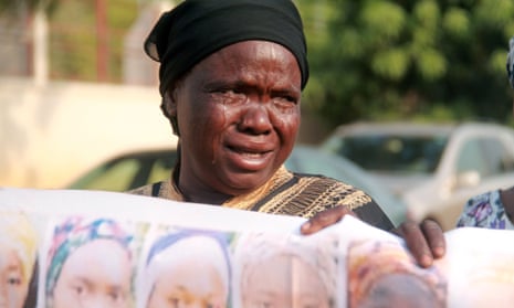 A Nigerian woman, the mother of a girl abducted by Boko Haram Islamists, cries as she displays a banner showing images of the missing girls.