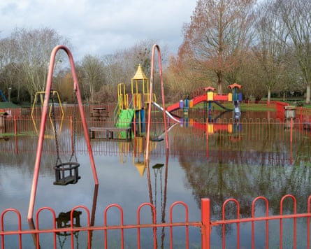 Water covers the ground of a fenced play area