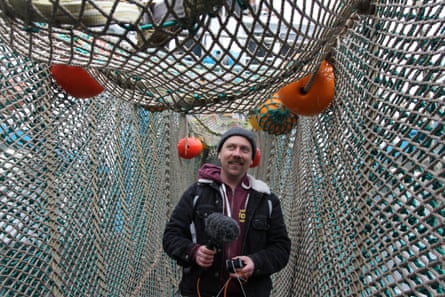 Man holds a microphone while walking underneath a fishing net